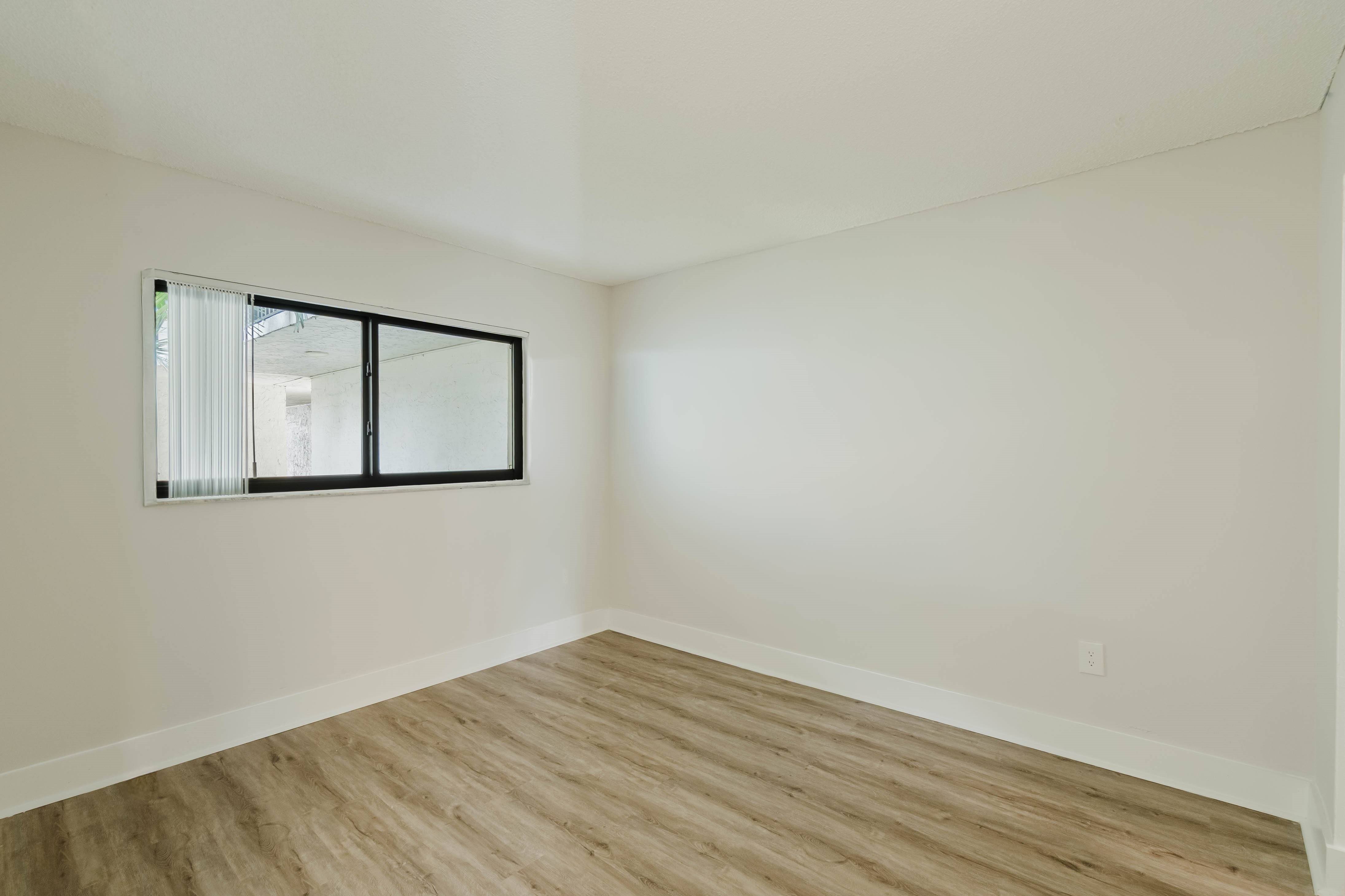 A room with a wooden floor and a large mirror on the wall.